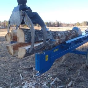 Klyvning av stort träd i mindre delar med vedklyvningsmaskin